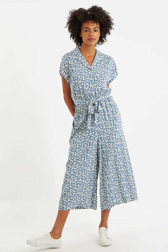 Louche London MAFALDA Periwinkle Blue Jumpsuit. Mafalda is the most perfect, relaxed fit jumpsuit ideal for summer strolls and picnics. Crafted in a cool blue ditsy print. Featuring a revere collar, button down front, self belt and cropped length trouser.